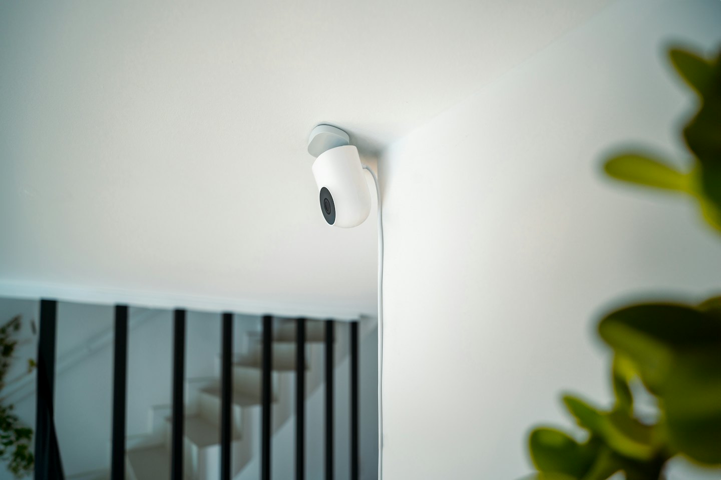 Modern security camera mounted on a white wall and ceiling.